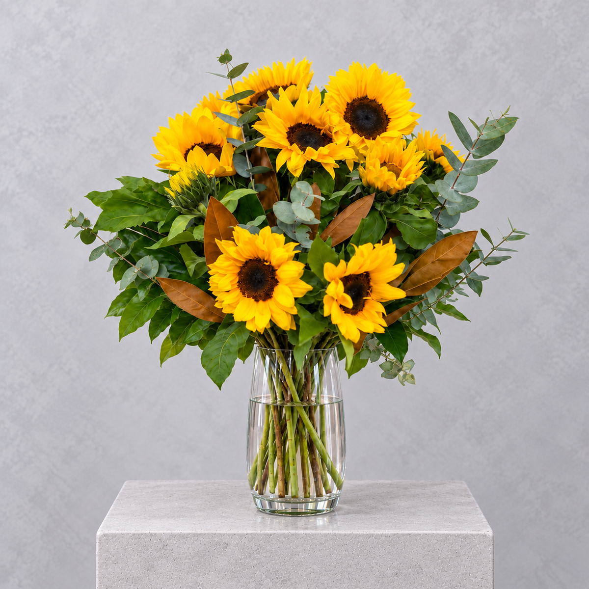 Golden sunflowers with eucalyptus in a glass vase, by Abdo Florist Sydney